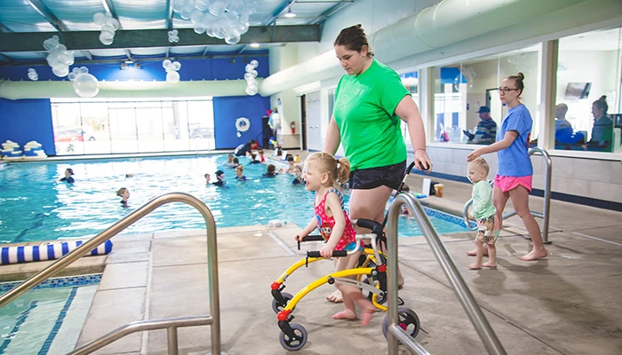 Child using walker during indoor aquatic therapy session