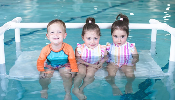 Three kids on floating bench in pool