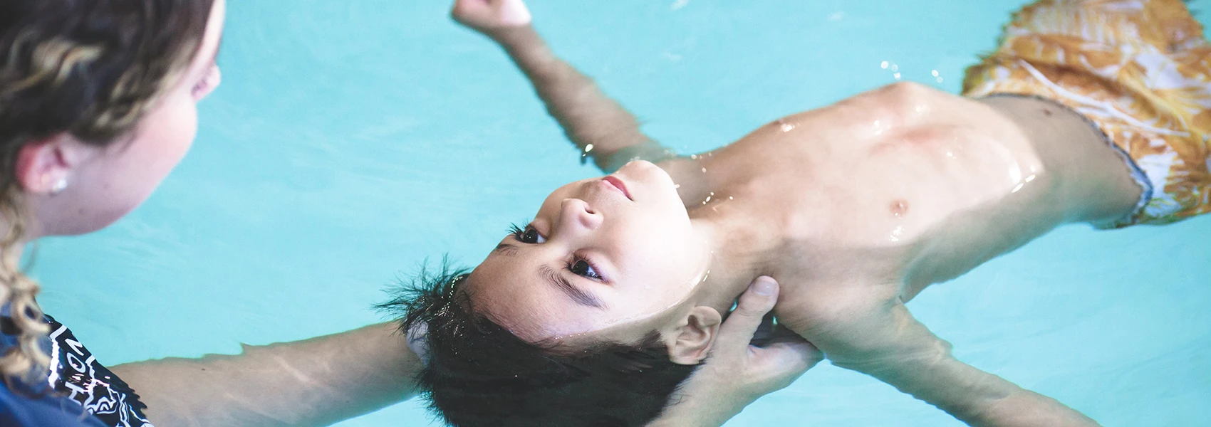 Child floating in pool during swimming lesson